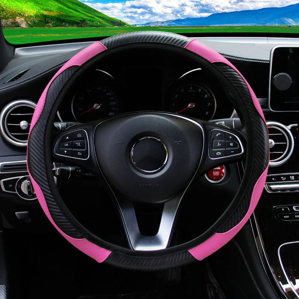 A close-up view of a black steering wheel with a pink PU carbon fiber cover inside a car interior.