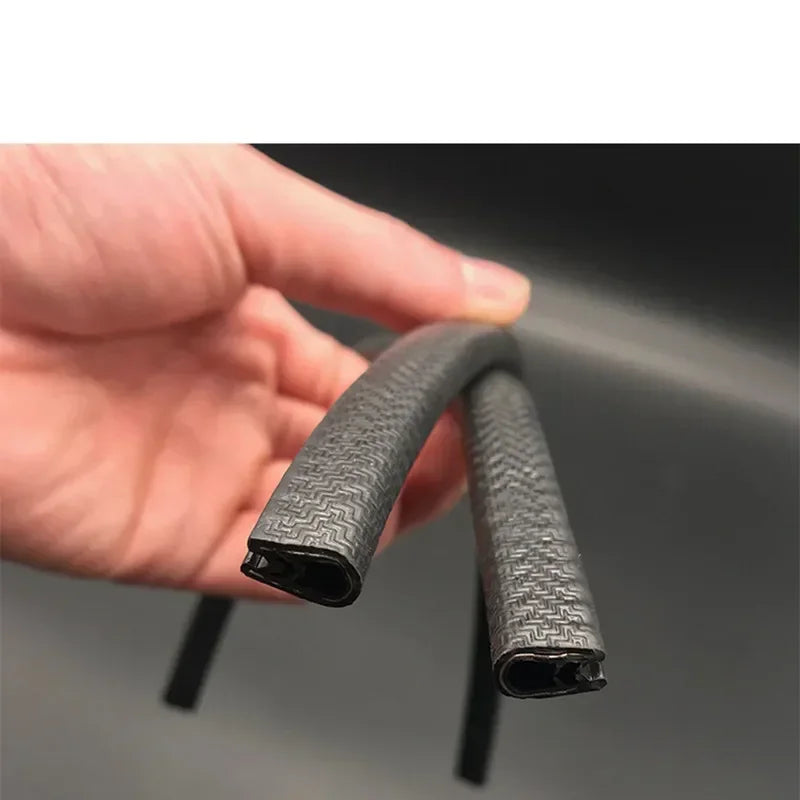 A hand holds a black rubber edge seal trim, showing its textured surface and profile.