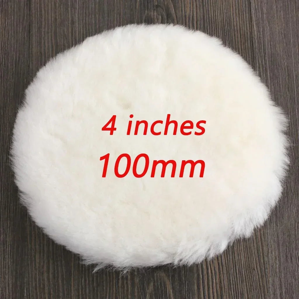 A round, white, fluffy polishing disc measuring 4 inches or 100mm resting on a dark wooden surface.