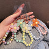 A hand holds a phone anti-loss lanyard featuring round bead pendants in pastel colors like pink, yellow, and orange.