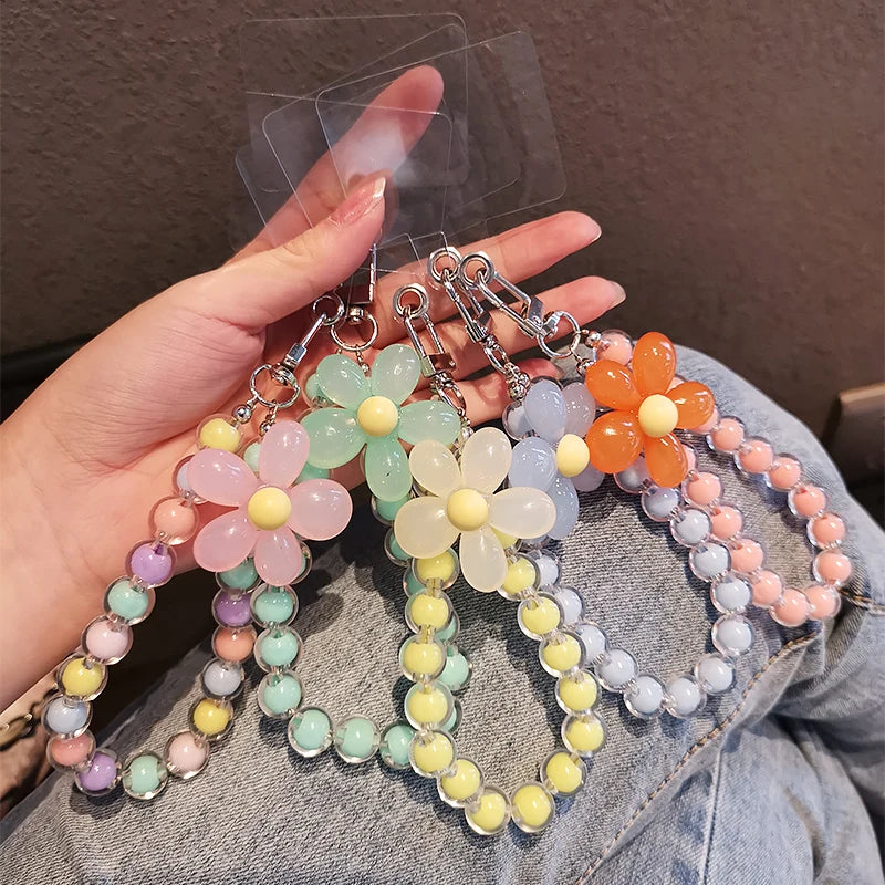 A hand holds a phone anti-loss lanyard featuring round bead pendants in pastel colors like pink, yellow, and orange.