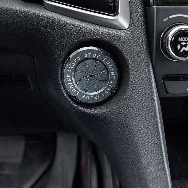 Close-up of a black decorative ignition cover for the engine start button on a vehicle dashboard.
