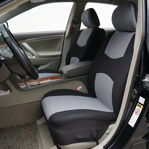 Innenansicht eines Autos mit Fahrersitz und Beifahrersitz, bedeckt mit grauen Stoffbezügen.