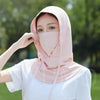 Une femme portant un masque facial respirant rose pâle et un haut blanc à l'extérieur.