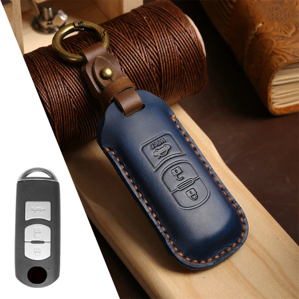 A dark blue leather car key fob cover attached to a brass ring, resting on a wooden surface.