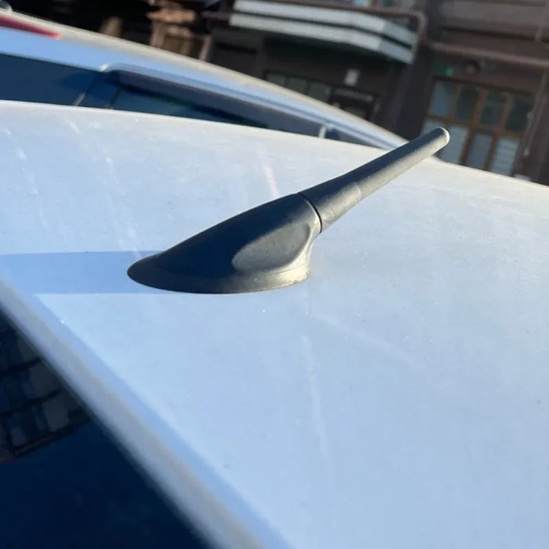 A black universal car radio antenna mount is visible on a white vehicle roof.