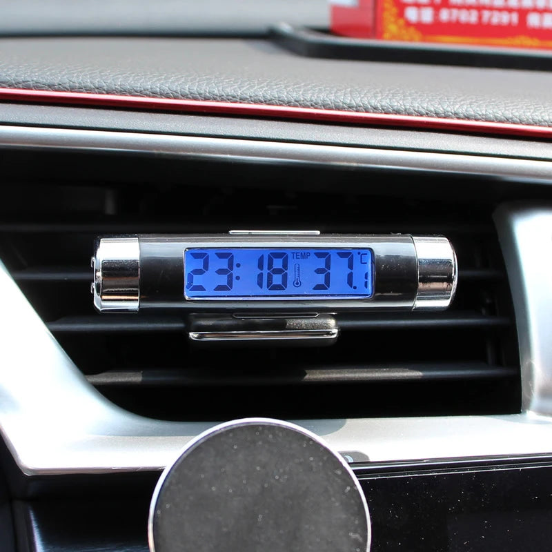 A digital car clock and thermometer with a blue backlight is displayed in a vehicle's interior dashboard.