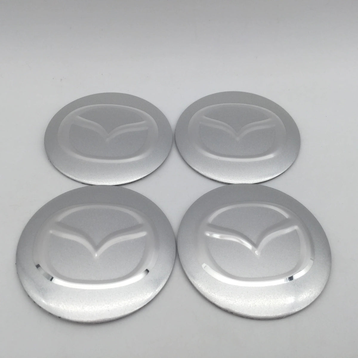 Four silver center caps or decals for 3D car wheel hubs.