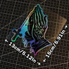 A decal of praying hands with a cross design shown against a grid background.