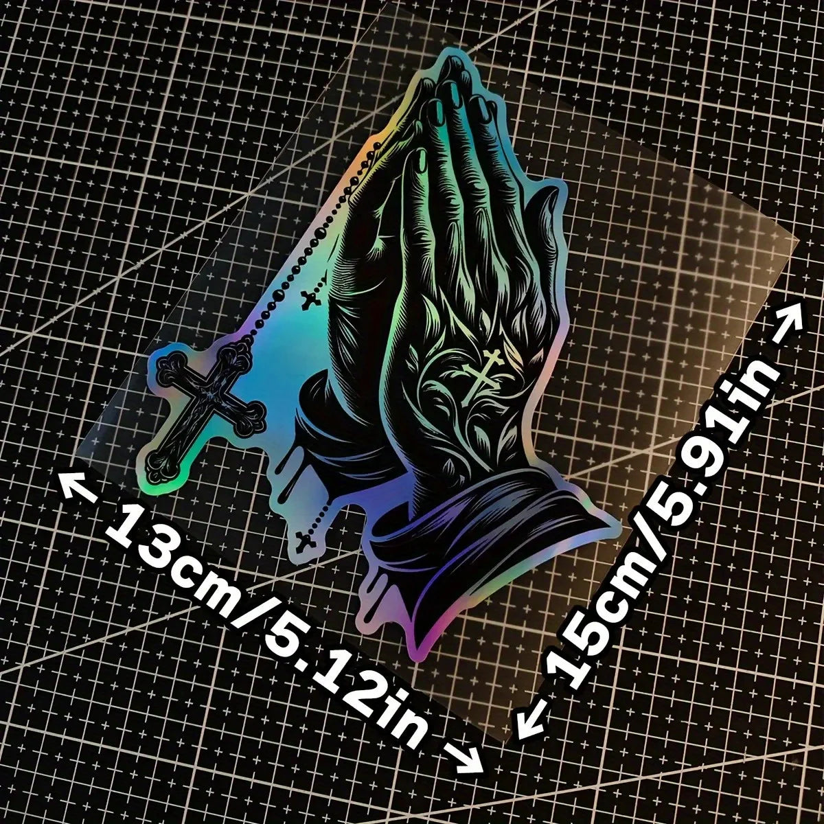 A decal of praying hands with a cross design shown against a grid background.
