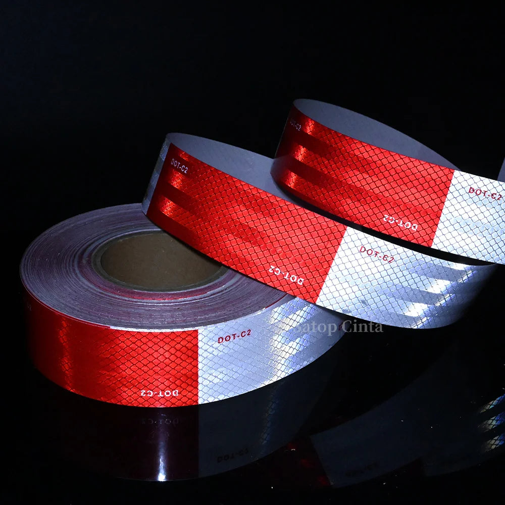 Rolls of high-visibility reflective safety tape showing red and white stripes against a dark background
