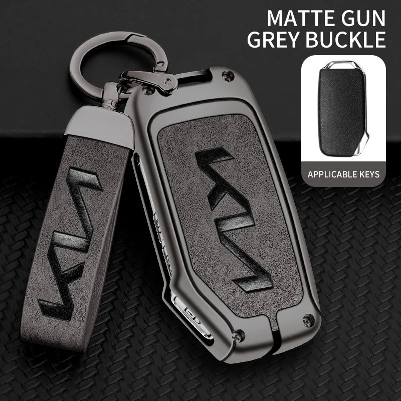 A matte grey buckle gun key case with a leather strap and metal loop, shown against a black background.