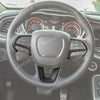 A close-up view of a steering wheel with a black leather cover and carbon fiber accents inside a car