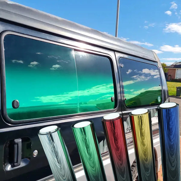 Close-up of a dark vehicle with tinted solar window film showing vibrant green and blue reflections.