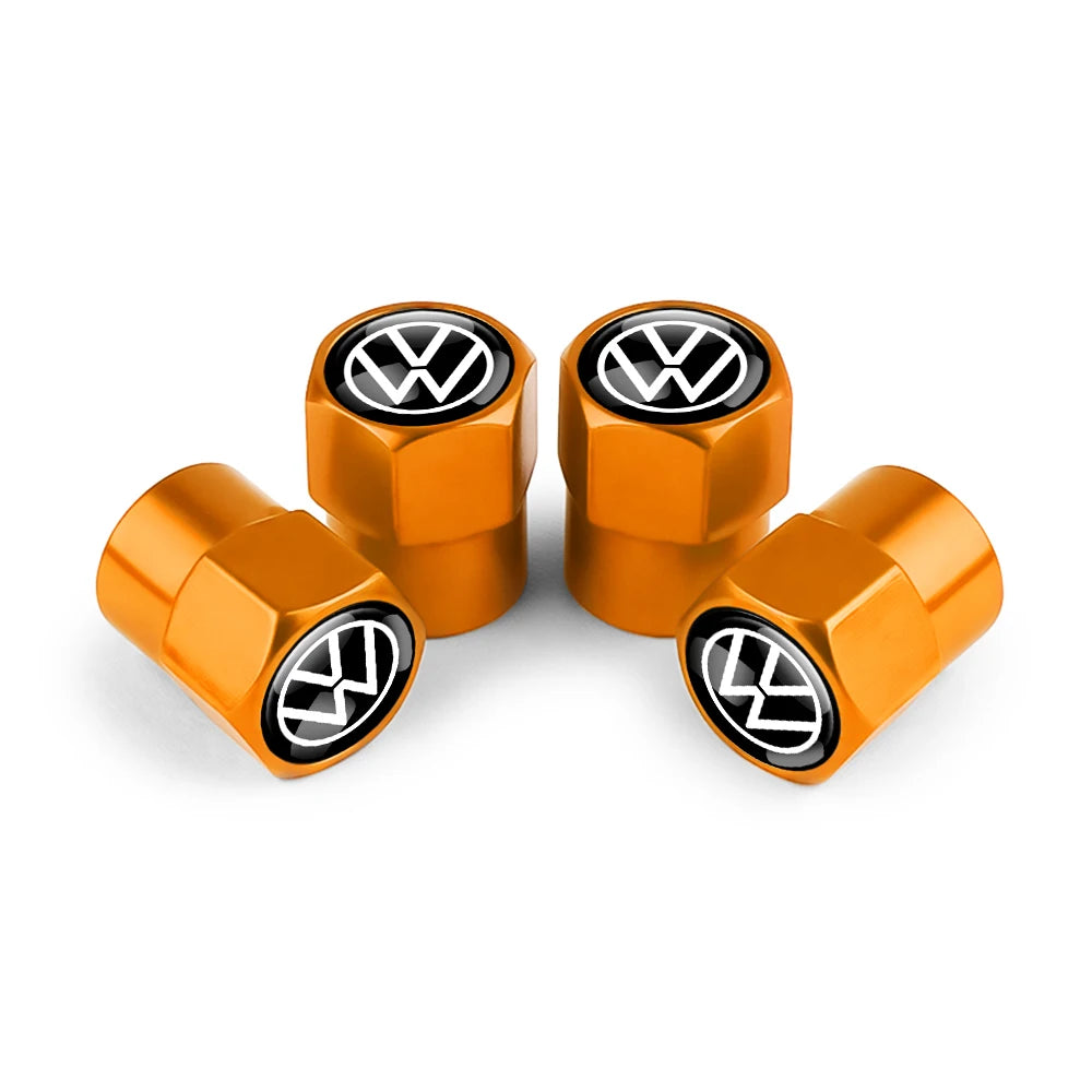 Three gold metal tire valve caps with black VW logos displayed on a white background.