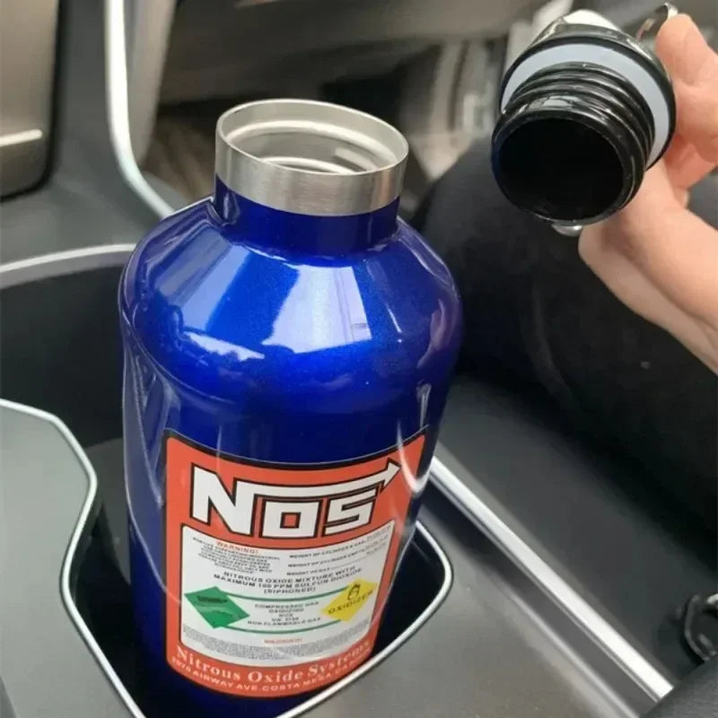 A blue insulated stainless steel travel kettle is shown being held by a hand.