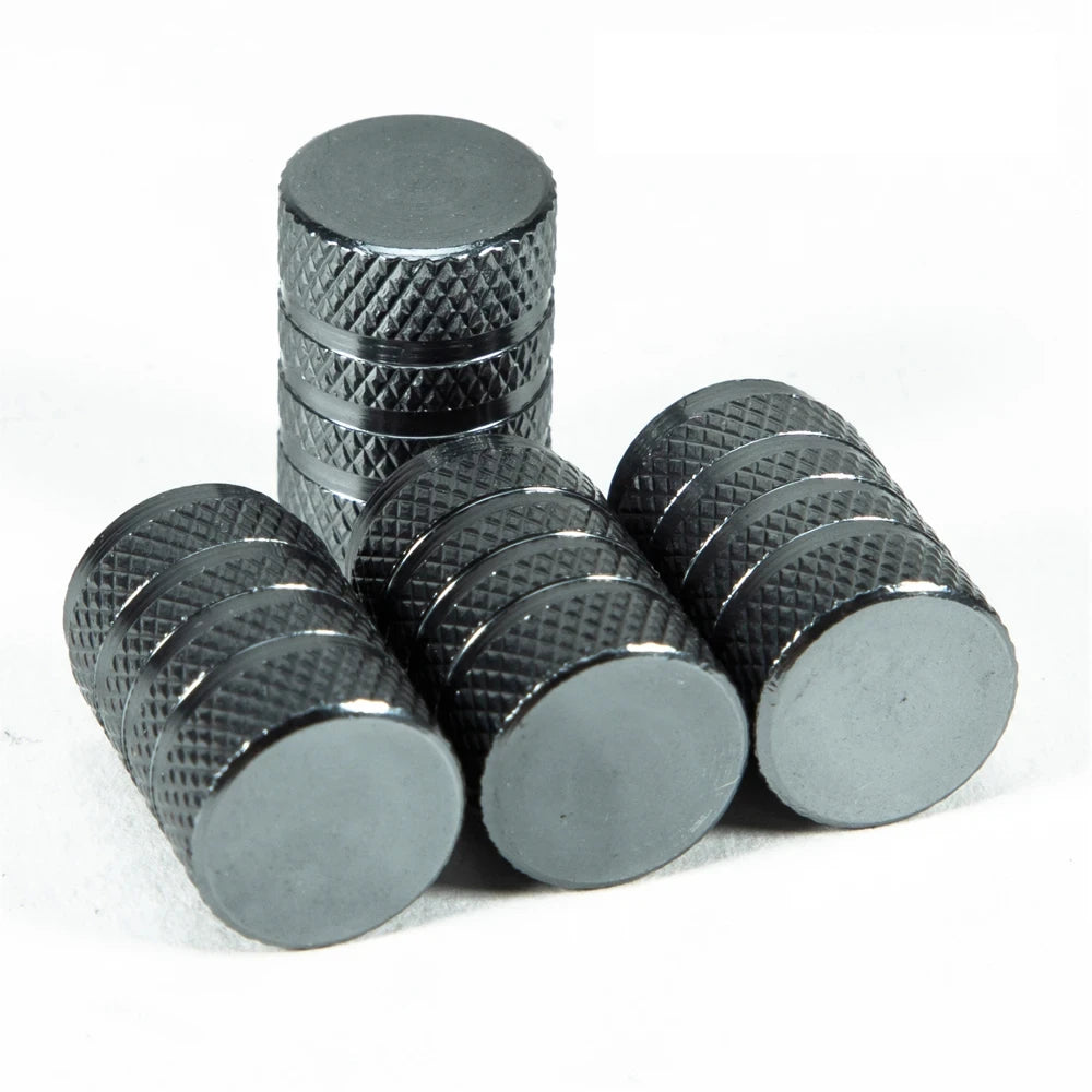 A set of black aluminum tire valve caps stacked and laid out on a white background.