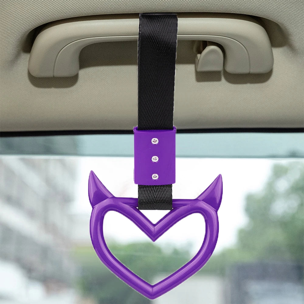 Purple heart-shaped handle accessory with a black strap hanging from a car door panel.