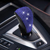 A close-up of a purple rhinestone gear shift knob cover protector installed on a car's transmission shifter.