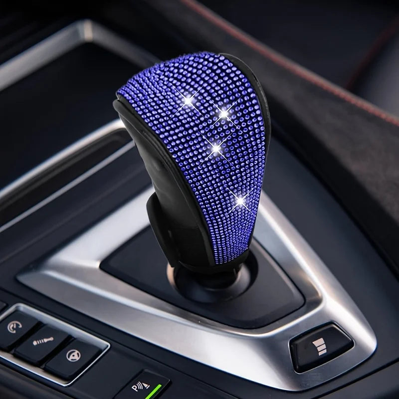 A close-up of a purple rhinestone gear shift knob cover protector installed on a car's transmission shifter.