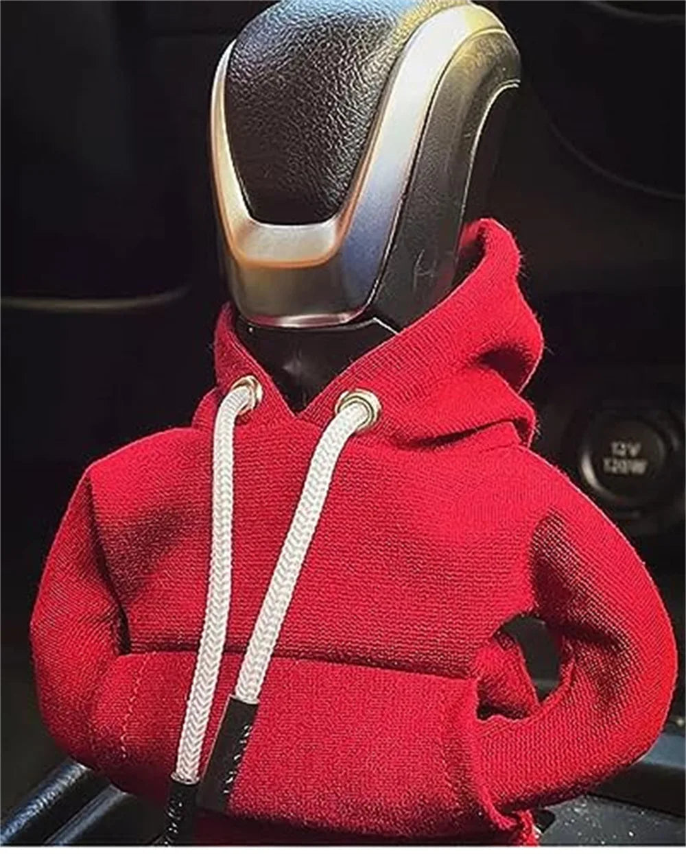 A red cozy knit hoodie is shown with a black cord attached, positioned over a gear shift cover.