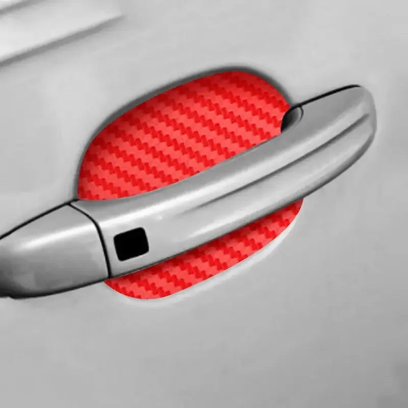 A close-up of a silver car door handle with a red protective film applied to the surface.