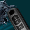 A close-up of a black car key cover with security features, shown next to shattered dark material.