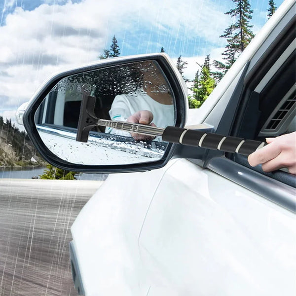 A hand uses a wooden glass cleaning tool to wipe the exterior of a car window.