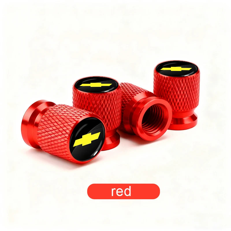Three red aluminum tire valve covers with yellow accents shown in a close-up view.