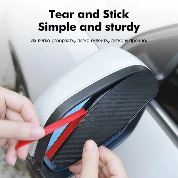 Hands are tearing a red piece of carbon fiber material from a black rain shield for a car rearview mirror.