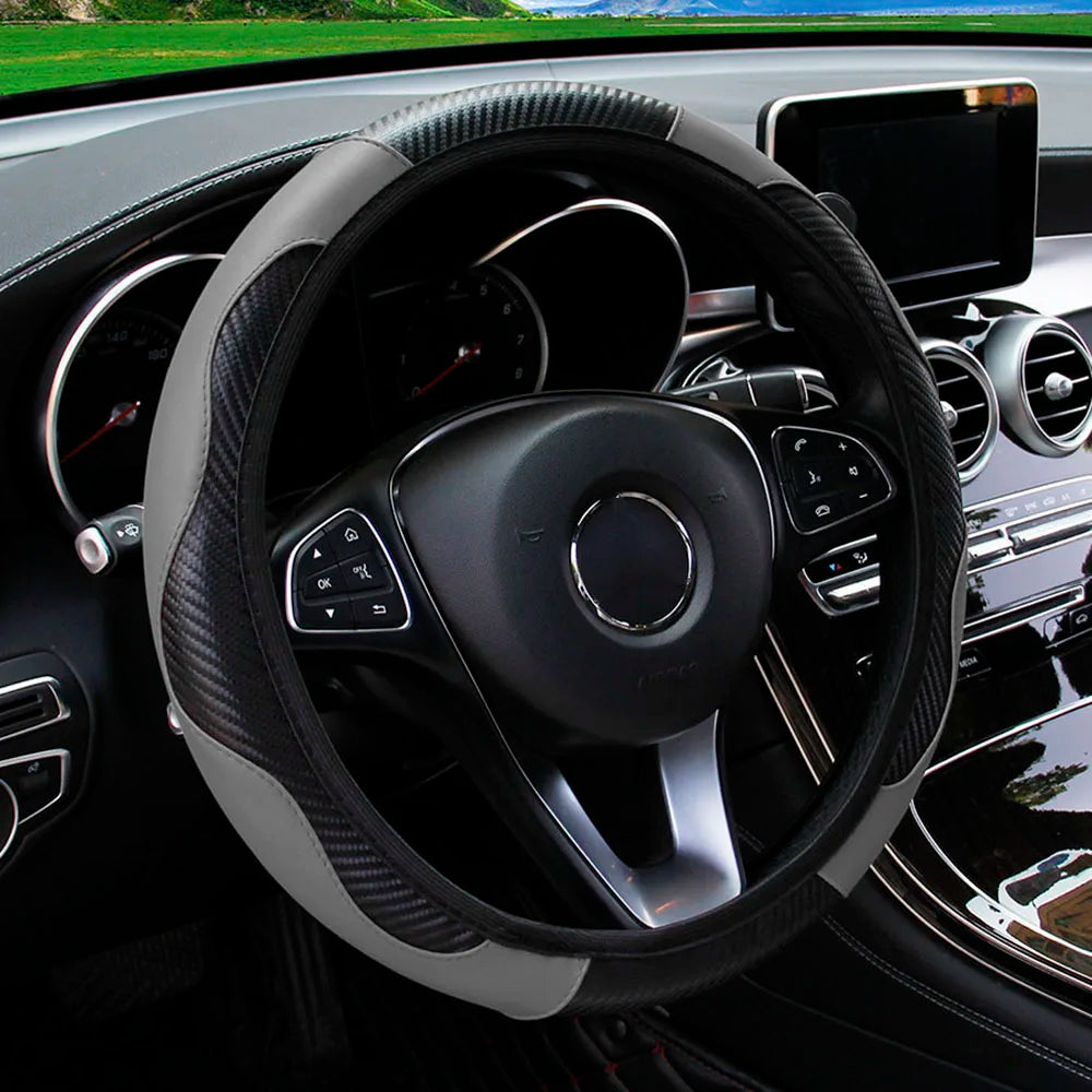 A close-up view of a black steering wheel with a PU carbon fiber cover and controls in a car interior.