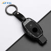 A black carbon fiber car key cover with a metal ring and strap is shown against a dark background.