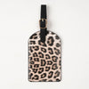 A black leather passport holder with gold hardware featuring a leopard print design.