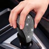 A hand is holding a black gear shift knob cover with sparkling rhinestone detailing.