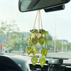 A string of green strawberry crochet decorations hangs from a rearview mirror inside a car.