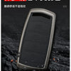 A close-up view of a black alloy material car key case resting on a dark, textured surface.