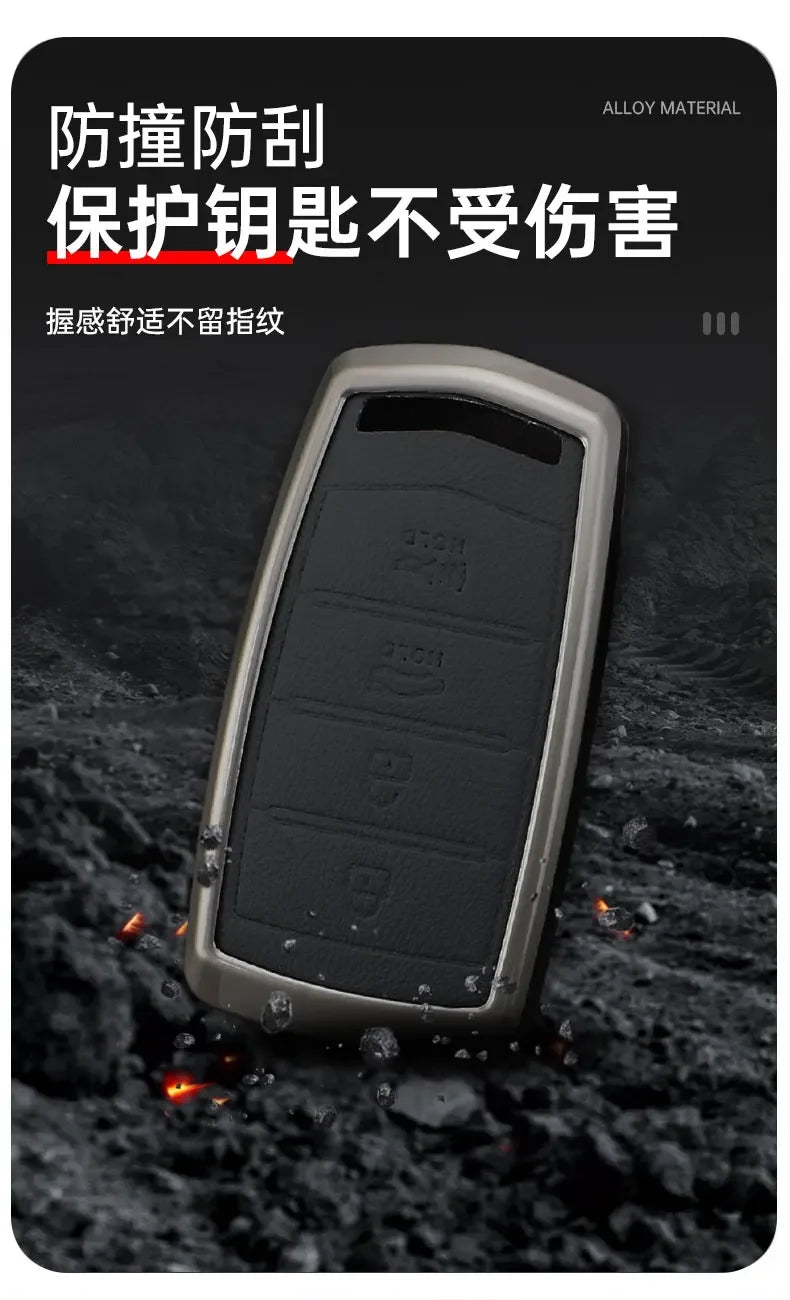 A close-up view of a black alloy material car key case resting on a dark, textured surface.