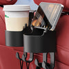 A black car seat cup holder hook is attached to a red car seat, holding a white cup and a smartphone.