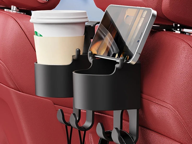 A black car seat cup holder hook is attached to a red car seat, holding a white cup and a smartphone.