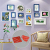 A gallery wall display featuring framed botanical and nature prints on a purple wall.