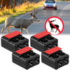 Four black car deer whistles with red tops shown next to a deer in a rural setting.