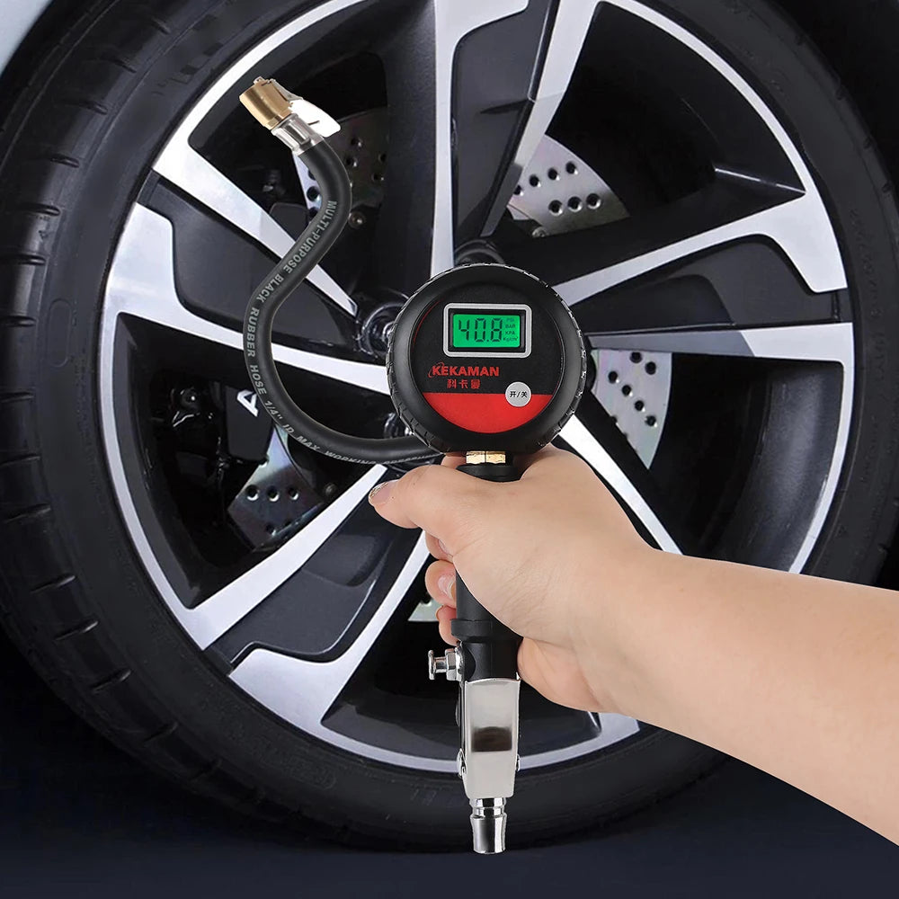 A hand holds a digital tire pressure gauge against a black car wheel, displaying the pressure reading.