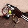 A sporty billiard bag charm keychain featuring a wooden paddle, a tennis ball, and a chocolate bar attached to leather and co