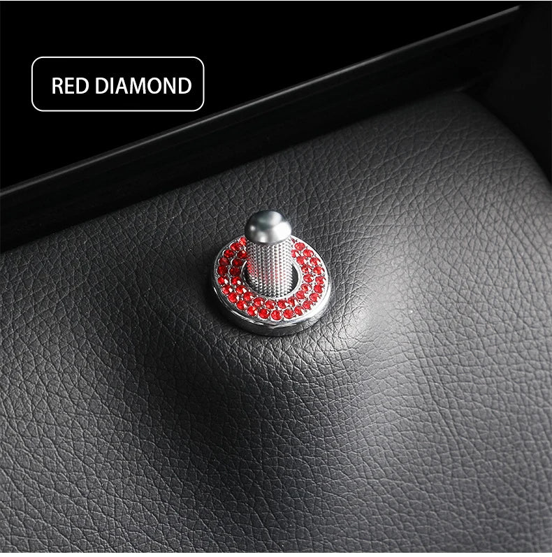 A close-up of a red diamond decorative car door lock pin set on a black leather surface.