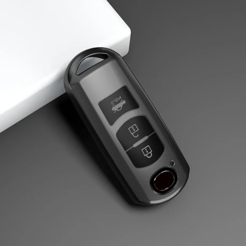 A close-up view of a universal car key cover for Mazda models, shown in a dark gray color.