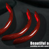 Three red carbon fiber steering wheel covers lying on a black fabric background.