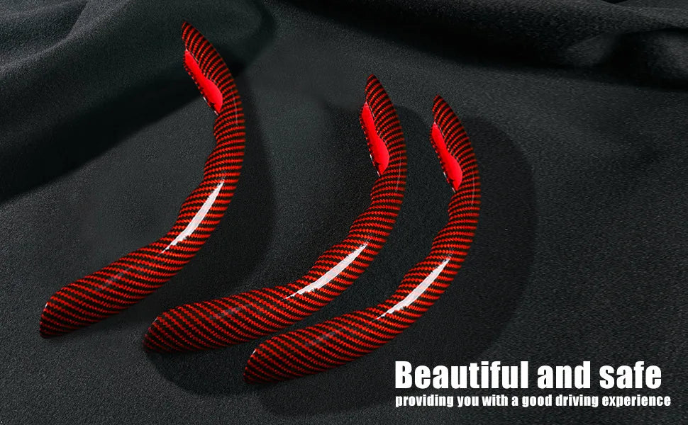 Three red carbon fiber steering wheel covers lying on a black fabric background.