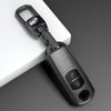 A black universal car key cover with a metal clasp and an electronic key fob is shown on a white surface.