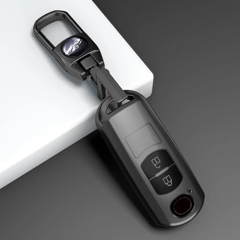 A black universal car key cover with a metal clasp and an electronic key fob is shown on a white surface.