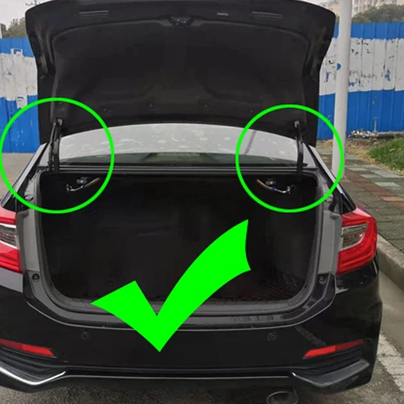 Vue arrière d'un coffre de voiture noire avec mécanisme de levage à ressort visible à travers le hayon.
